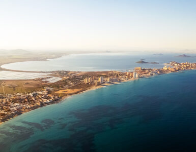 Aerial picturesque panoramic horizontal image, drone point of view La Manga del Mar Menor townscape and seaside spit of turqiouse Mediterranean Sea. Murcia, Spain. Travel and holidays concept