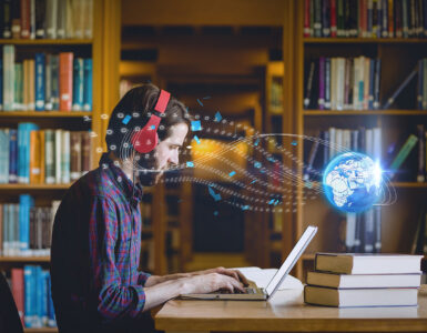Composition of digital globe over male student using laptop in library. global education, digital interface, technology and networking concept digitally generated image.